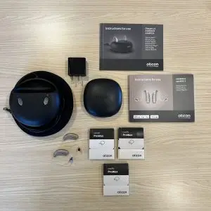 used oticon more 2 hearing aids product listing with standard charger, hard carrying case, original manuals, and wax guards