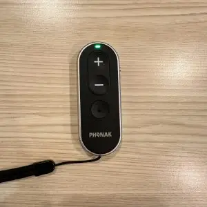 used phonak remote control with green light on laying on table