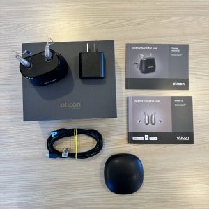 used oticon intent 2 hearing aids in charger on box with manuals, carrying case, and cord