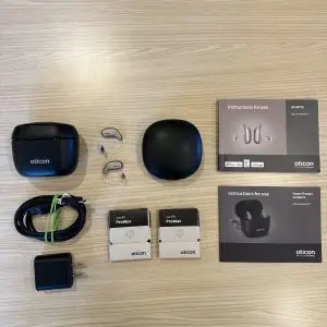 used oticon intent 1 listing with premium charger, cable, wall plug, hard case, wax guards, charger and hearing aid manuals, and hearing aids
