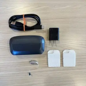used resound vivia hearing aid with charger, cord, wall plug, and wax guards